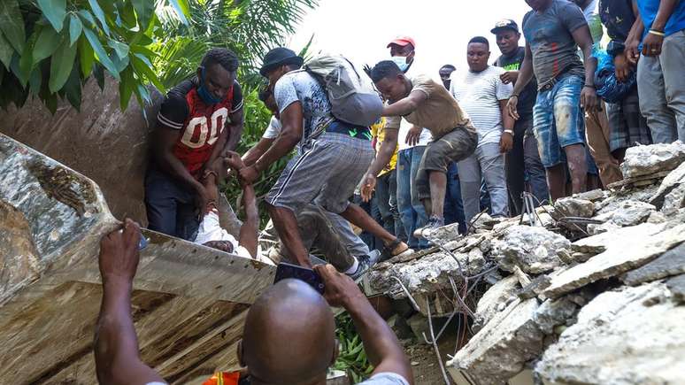 Homens tentam resgatar um sobrevivente debaixo de destroços
