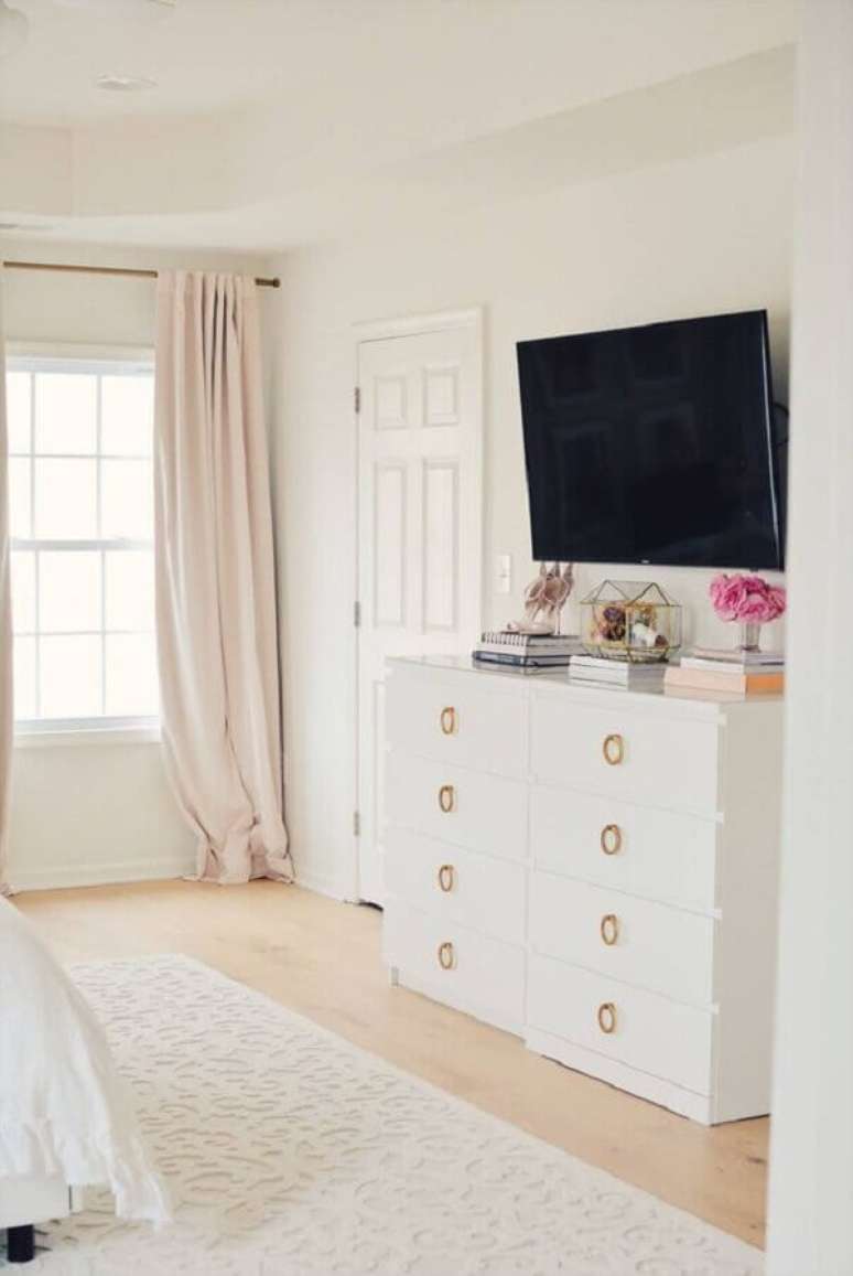 26. Cômoda branca para quarto grande decorado com TV na parede – Foto: Pinterest
