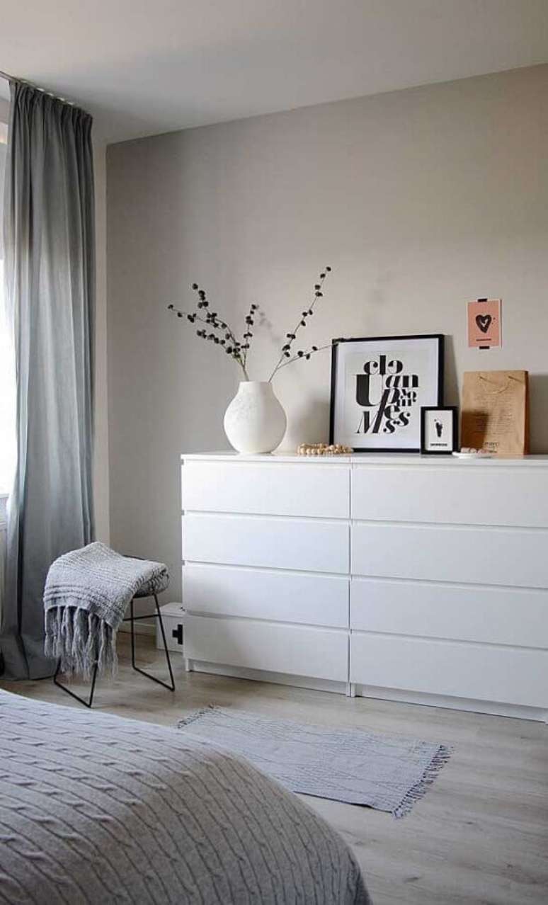 24. C&ocirc;moda branca para quarto de casal minimalista decorado com cortina cinza e piso de madeira clara &ndash; Foto: Apartment Therapy