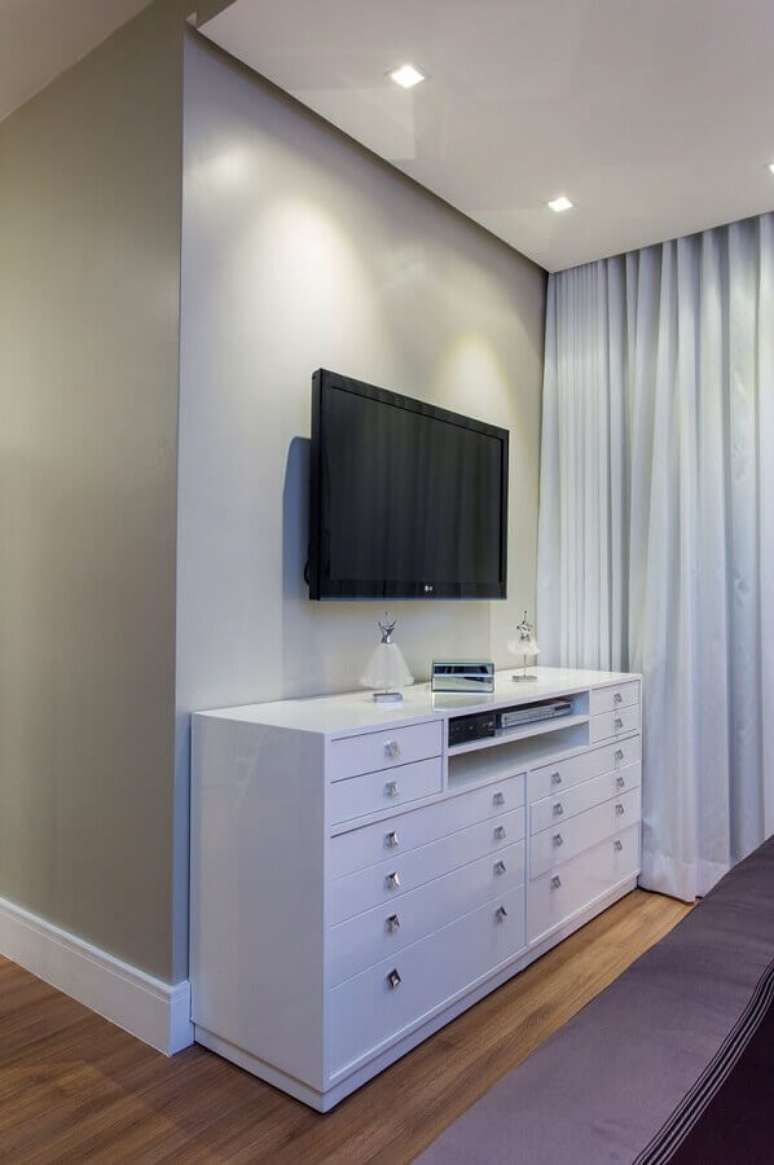 25. Cômoda branca para quarto decorado em cores claras com TV na parede – Foto: Bruno Sgrillo