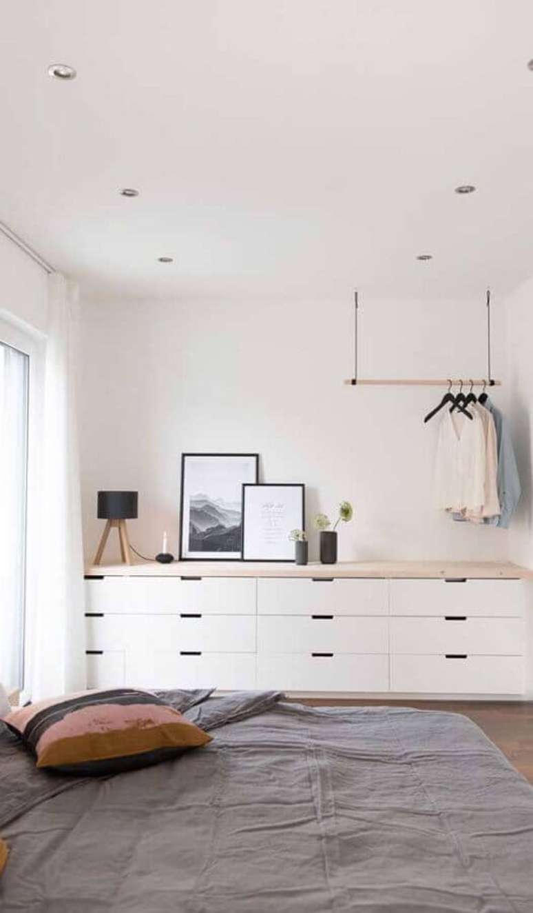 6. Cômoda branca grande para quarto de casal minimalista decorado com cabideiro de teto – Foto: Pinterest