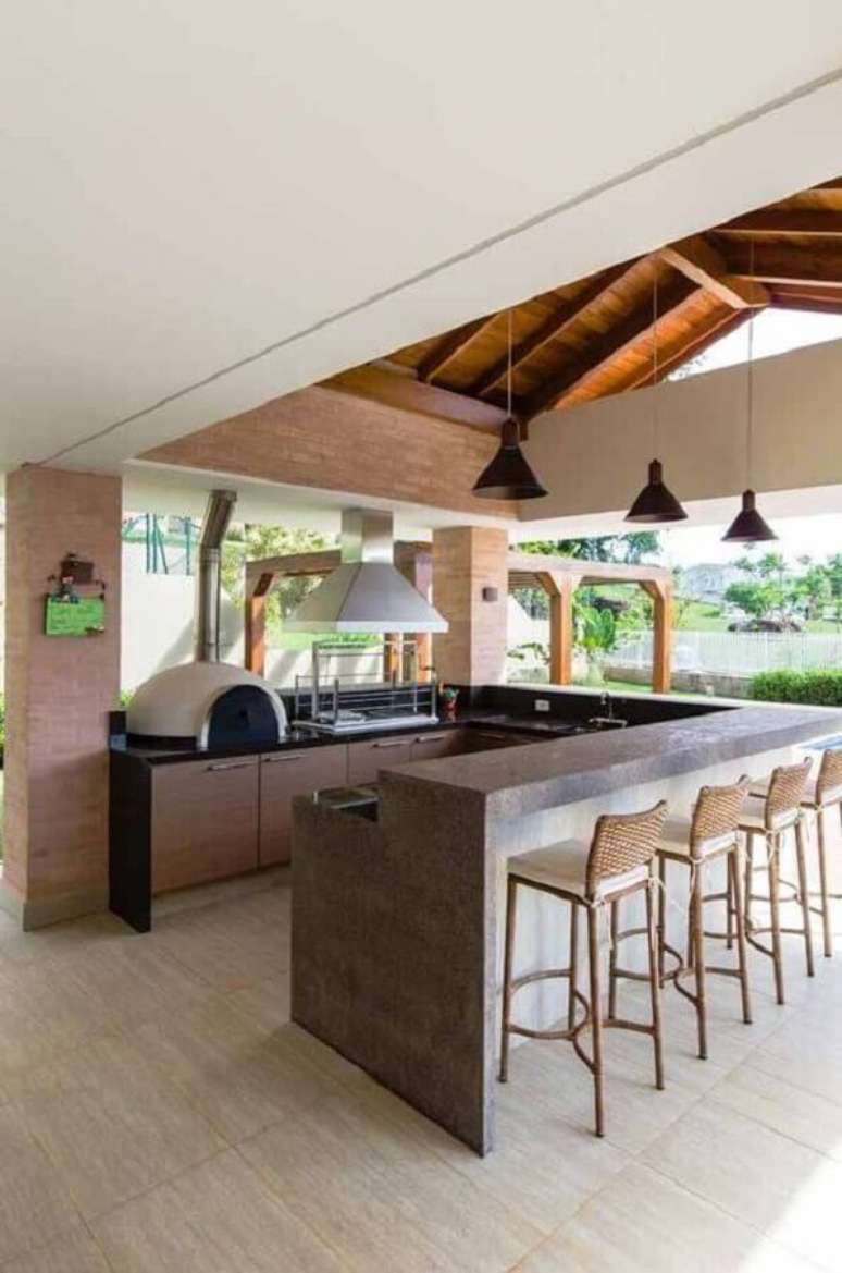 12. Decora&ccedil;&atilde;o com lustre para &aacute;rea gourmet com churrasqueira de vidro e forno de pizza &ndash; Foto: Pinterest