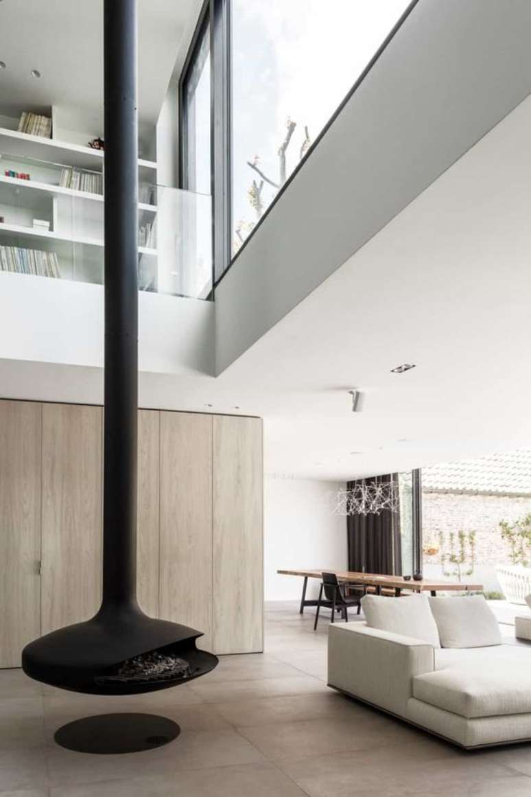 24. Lareira suspensa preta perto do sof&aacute; branco na sala de estar de conceito aberto &ndash; Foto Abs Bouwteam