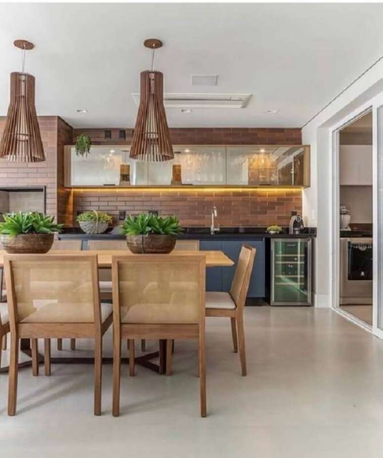 9. Lustre para &aacute;rea gourmet grande decorada com cadeiras de madeira e parede de tijolinho &ndash; Foto: Fashion Bubbles