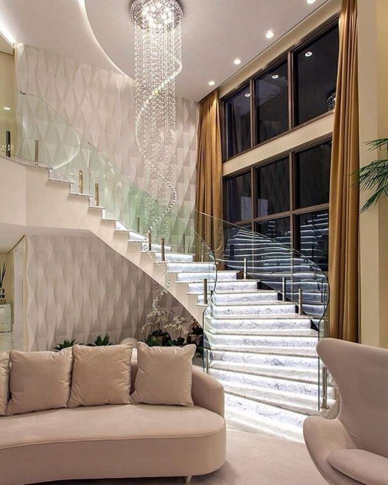 8. Modelo de escada p&eacute; direito duplo com ilumina&ccedil;&atilde;o embutida e guarda corpo de vidro. Fonte: Revista Viva Decora 2