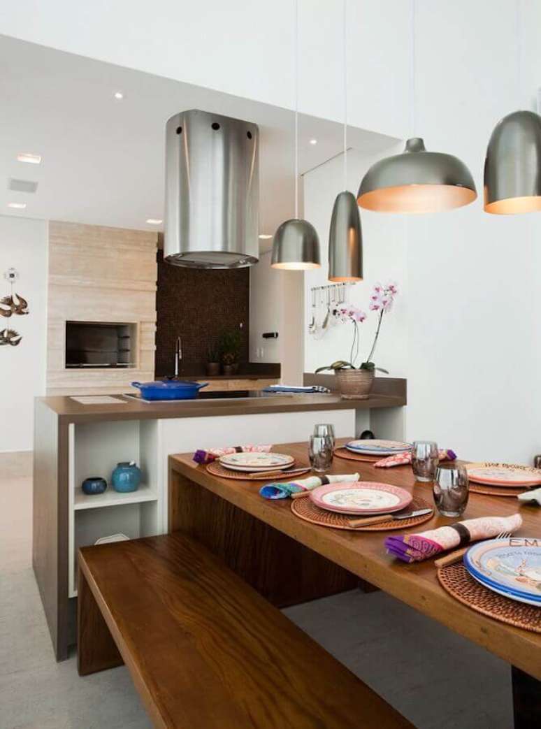 36. Lustre para área gourmet decorada com mesa de madeira e coifa redonda – Foto: Art Maison