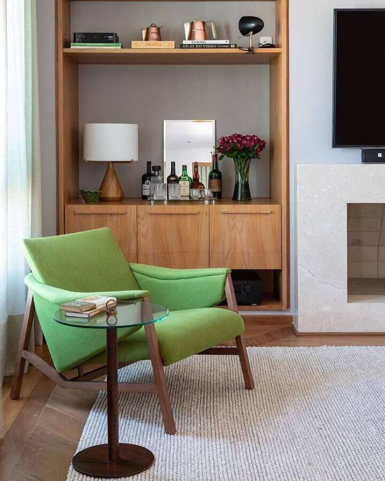 58. Poltrona confortável para sala de TV decorada com estante de madeira – Foto: Adriana Valle e Patrícia Carvalho