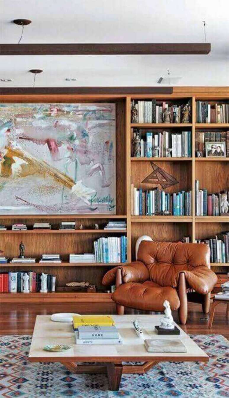 56. Poltrona confortável para sala de estar decorada com estante de madeira para livros – Foto: Pinterest