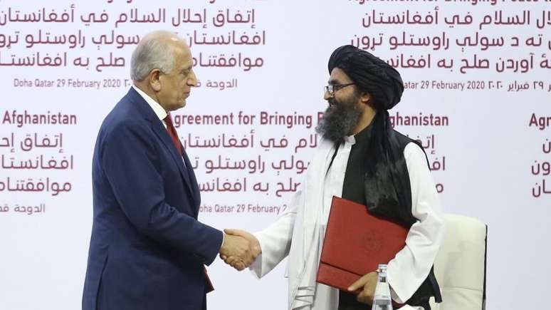 O enviado dos EUA, Zalmay Khalilzad e o líder talibã, Mullah Abdul Ghani Baradar, na assinatura do Acordo de Doha.