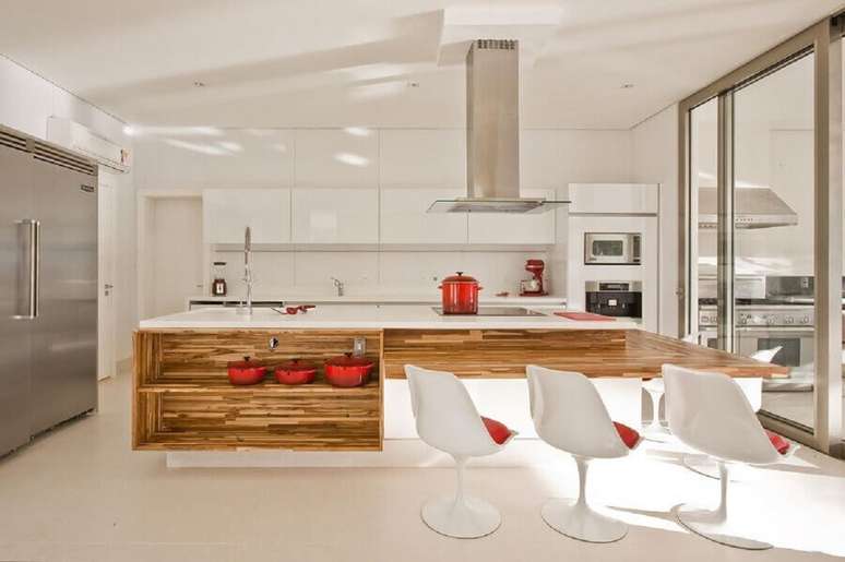 48. Decoração para cozinha aberta com ilha branca com bancada e nichos de madeira e cadeiras brancas – Foto: Marí Aní Oglouyan