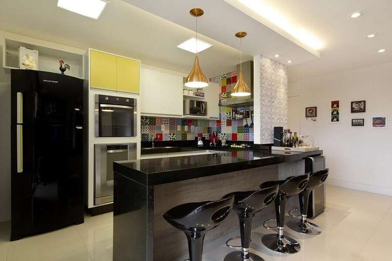37. Decoração de cozinha aberta com revestimento colorido e banquetas pretas – Foto: Juliana Conforto