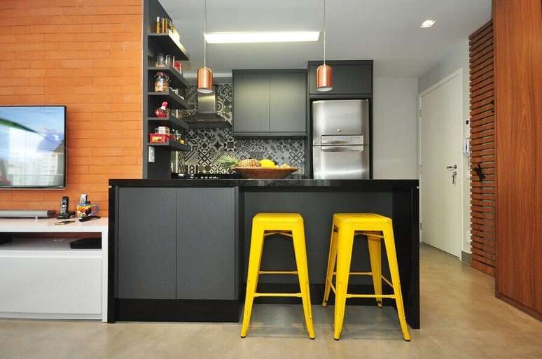 33. Decoração com banqueta amarela para cozinha aberta com sala de TV integrada – Foto: Condecorar Arquitetura e Interiores