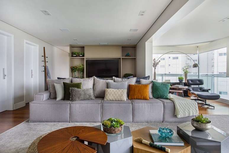 7. Decoração de sala grande com almofadas para sofá cinza sem braço – Foto: Tria Arquitetura