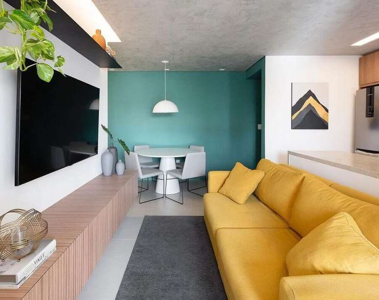 56. Ideia de cores para sala pequena e moderna decorada com sofá amarelo e parede azul – Foto: Fantato Nitoli