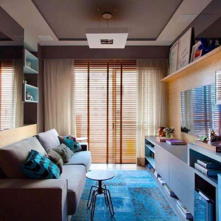 38. Cores para sala pequena decorada com tapete azul e persiana de madeira – Foto: Juliana Pippi