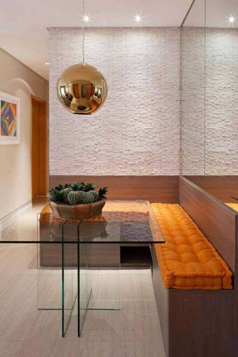 11. Cores para sala de jantar pequena decorada com mesa de vidro e canto alemão com almofadas laranja – Foto: Decor Fácil