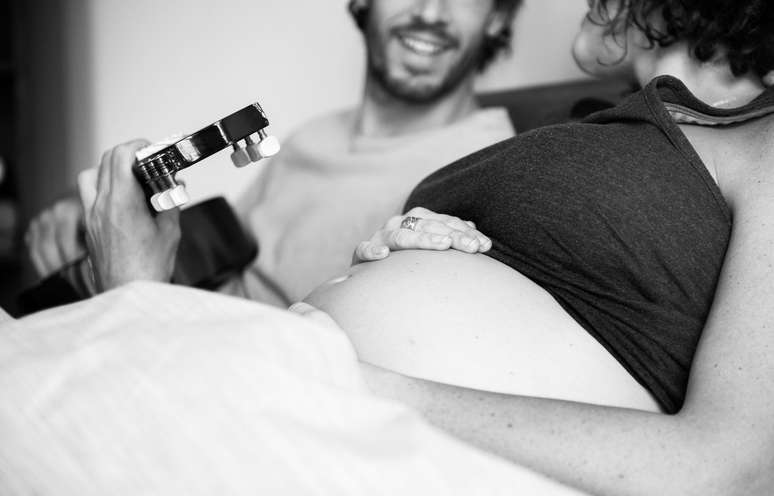 Homem tocando música e mulher segurando a barriga de grávida
