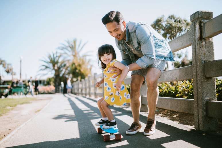 Pai ajudando a filha a andar de skate
