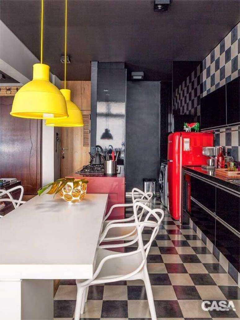 9. Piso xadrez para cozinha preta decorada com luminária amarela e geladeira vermelha – Foto: Casa Abril