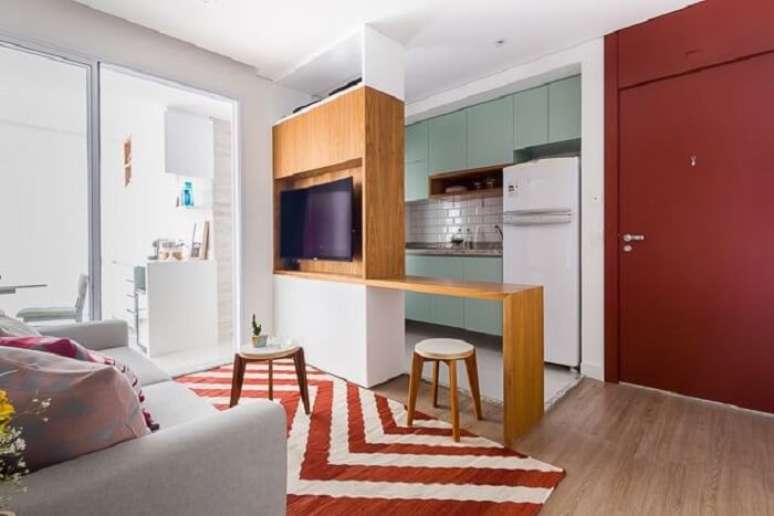 8. Sala pequena planejada com sofá cinza e tapete estampado vermelho. Projeto de Duda Senna