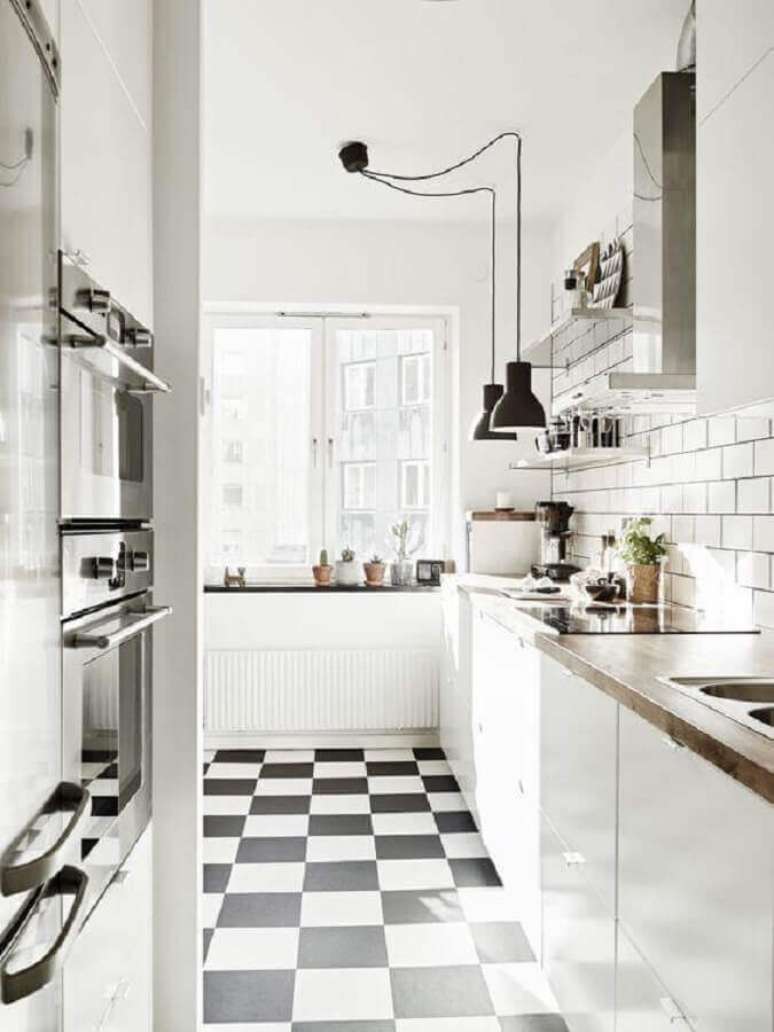 14. Cozinha branca decorada com bancada de madeira e piso xadrez preto e branco – Foto: My Ideal Home