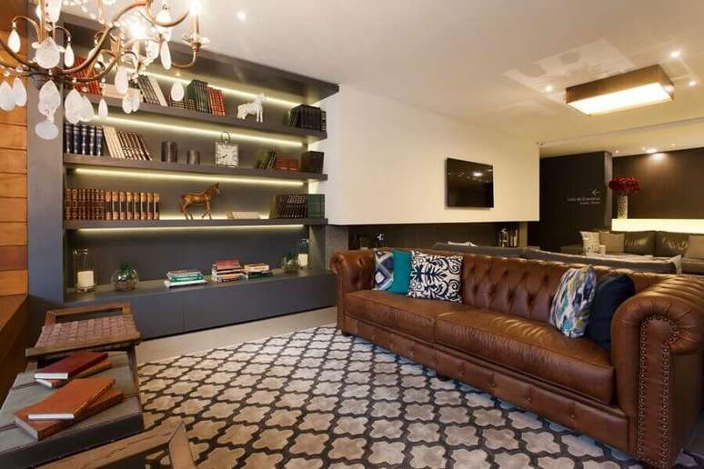 40. Tipos de sofás de couro capitonê para decoração de sala com estante cinza planejada – Foto: BG Arquitetura