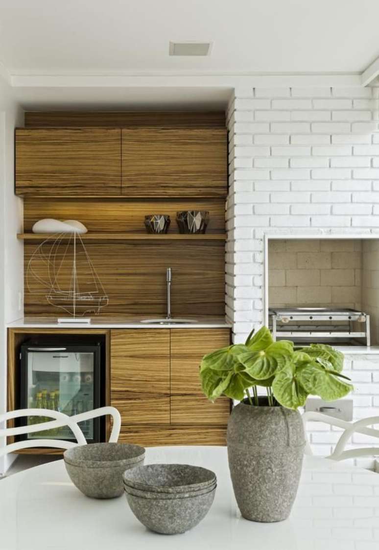 24. Churrasqueira pequena revestida com tijolinho branco moderno e gabinete planejado de madeira – Foto Diego Revollo
