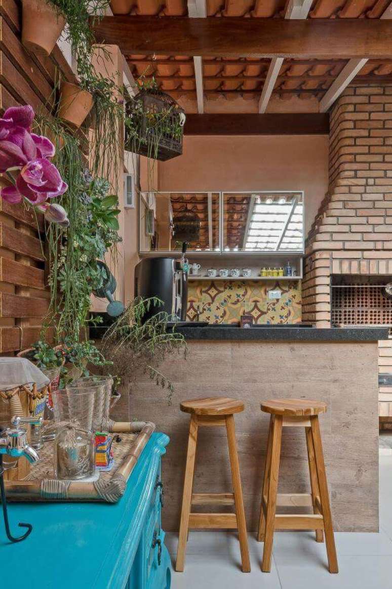 67. Área gourmet com churrasqueira pequena de tijolinho e jardim vertical perto da mesa azul – Foto Kathia Pimmenta