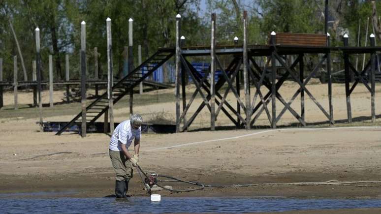 Homem tenta tirar água de um ramo quase seco do rio Paraná