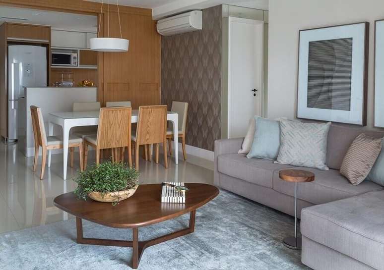 21. Decoração de sala de estar e jantar integrada com sofá cinza e mesa de centro diferente – Foto: Ana Yoshida