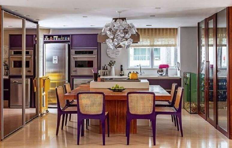 58. Lustre moderno para decoração de cozinha planejada com ilha e bancada de madeira com cadeiras roxas – Foto: Maricy Borges