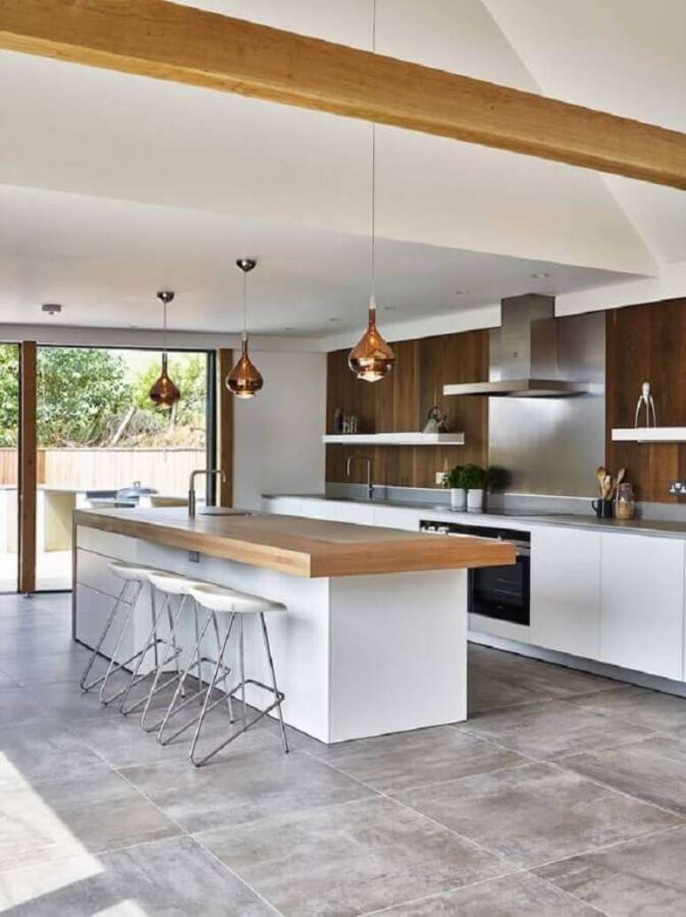31. Cozinha planejada grande com ilha decorada com bancada de madeira e lumin&aacute;ria cobre &ndash; Foto: Houzz