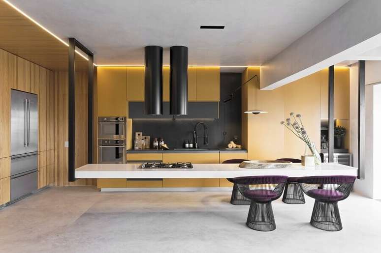 26. Cozinha planejada com ilha moderna decorada com arm&aacute;rios amarelos e cadeira estofada &ndash; Foto: Diego Revollo