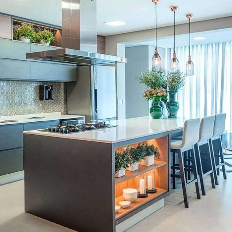 27. Cozinha planejada com ilha moderna decorada com luminária de vidro e nichos com iluminação – Foto: Houzz