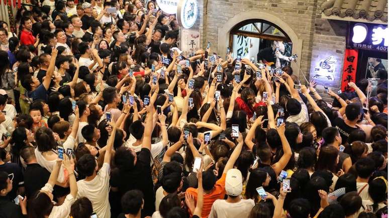 Fãs gravam vídeos em seus smartphones enquanto a boyband Modern Brothers se apresenta durante um webcast ao vivo na Andong Old Street em 30 de junho de 2018 em Dandong, província de Liaoning na China.