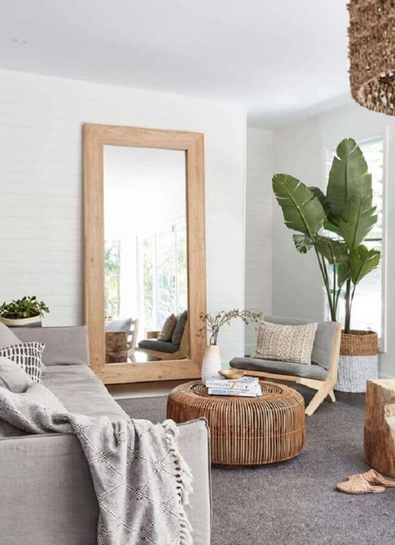 36. Espelho na sala de estar cinza e branca decorada com poltrona de madeira e vaso de planta no chão – Foto: Apartment Therapy