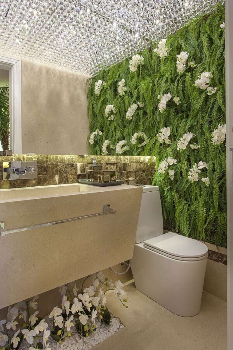 41. Lustre de cristal para banheiro bonito de luxo decorado com jardim vertical – Foto: Iara Kilaris
