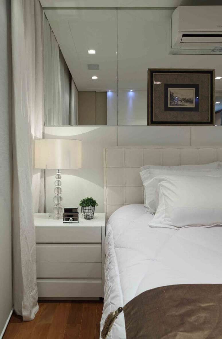 48. Parede espelhada para quarto branco decorado com cabeceira almofadada – Foto: Decor Fácil