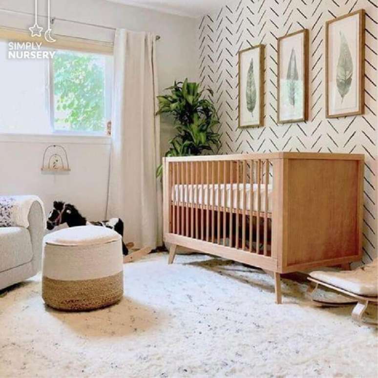 9. Berço cor de madeira para quarto branco decorado com vaso de planta e puff redondo – Foto: Simply Nursery