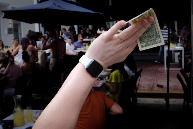 Homem acena com nota de dólar na mão em bar em Miami Beach, Flórida, EUA
06/03/2021
REUTERS/Marco Bello