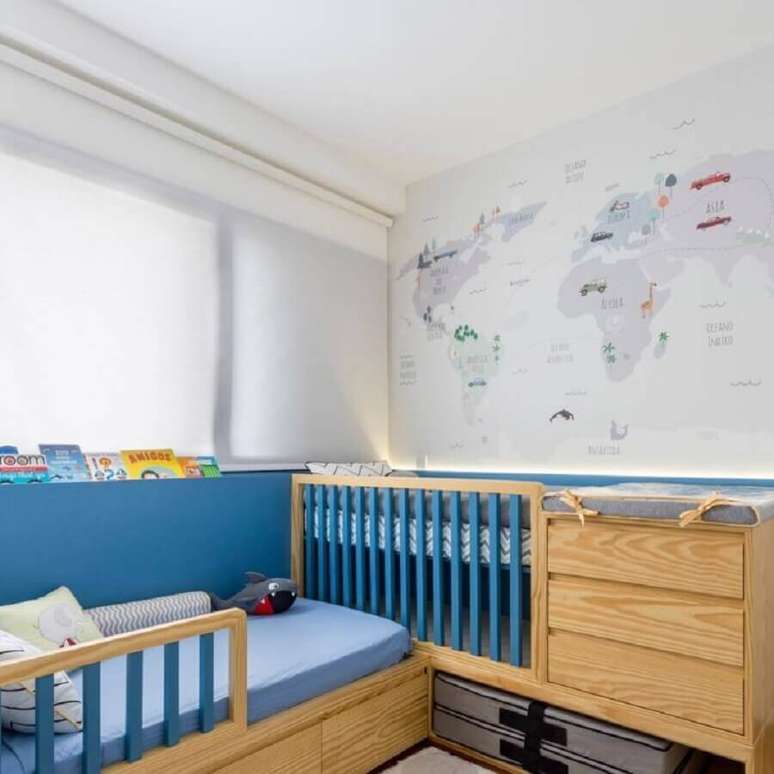 11. Berço de madeira com gaveta e trocador para quarto de bebê azul e branco decorado com mapa na parede – Foto: UEBAA