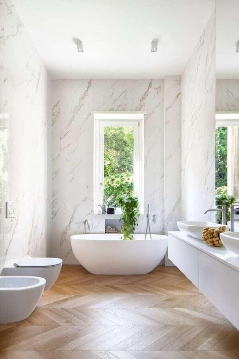 54. Parede de mármore para decoração de banheiro com piso de madeira e banheira de imersão – Foto: HomeAdore