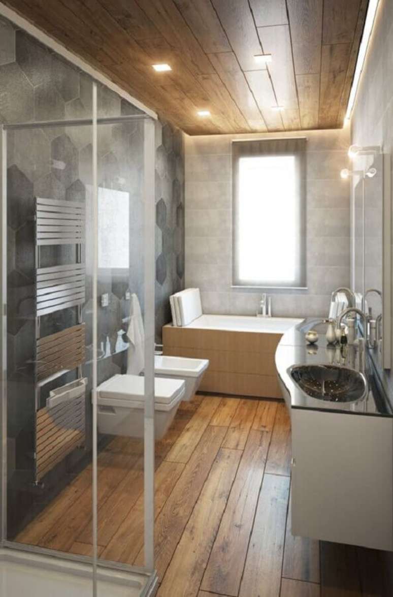 57. Revestimento cinza hexagonal para decoração moderna de banheiro com piso de madeira – Foto: Voglia di Ristrutturare
