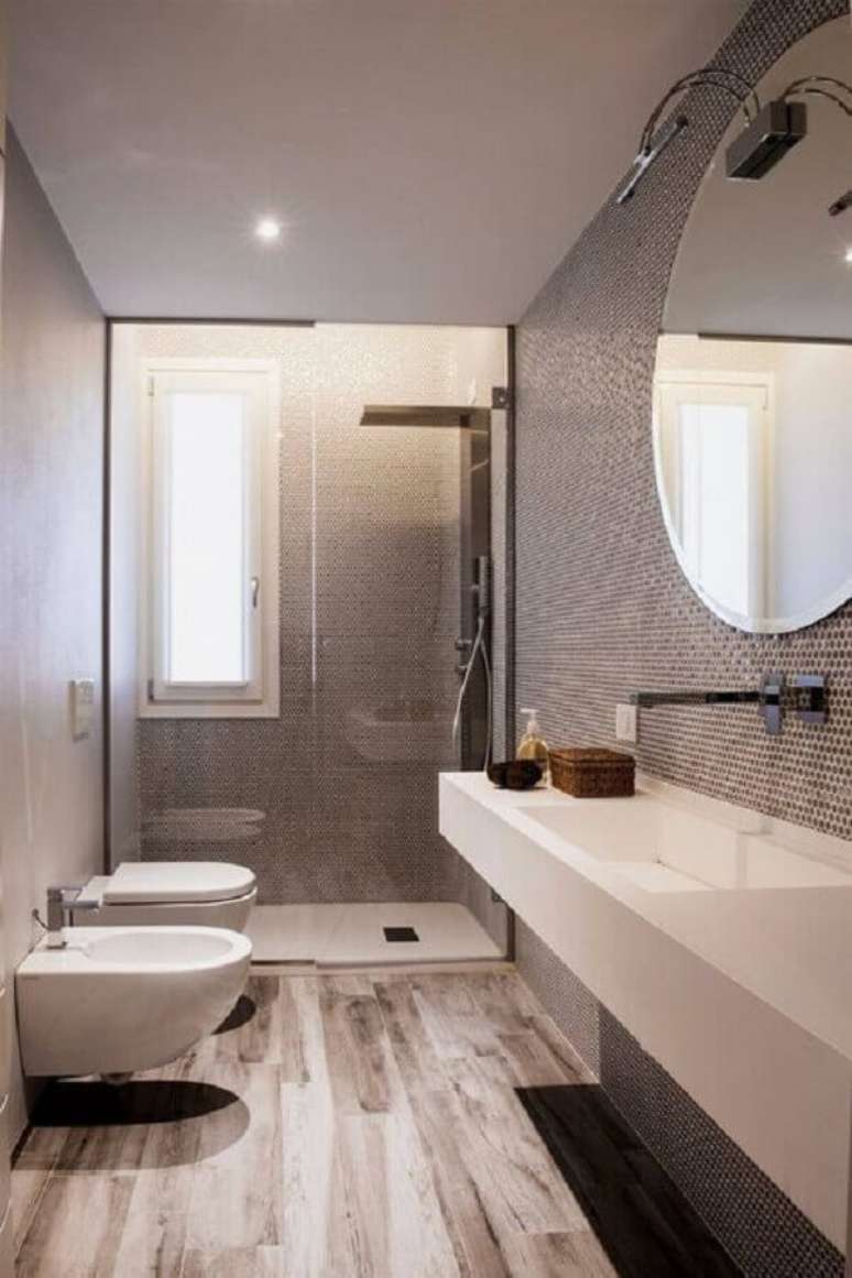 42. Decoração moderna para banheiro com piso de madeira e espelho redondo bisotado – Foto: Voglia di Ristrutturare