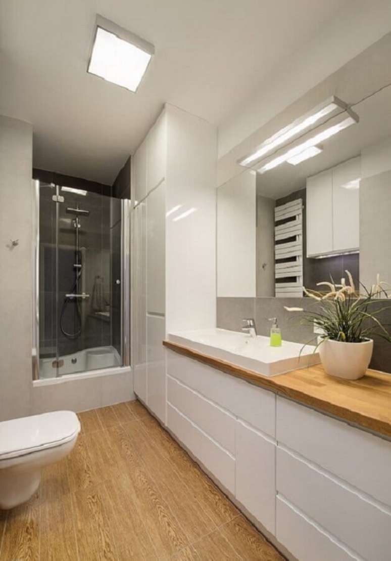 9. Armário planejado para decoração de banheiro pequeno com piso de madeira – Foto: Homebook