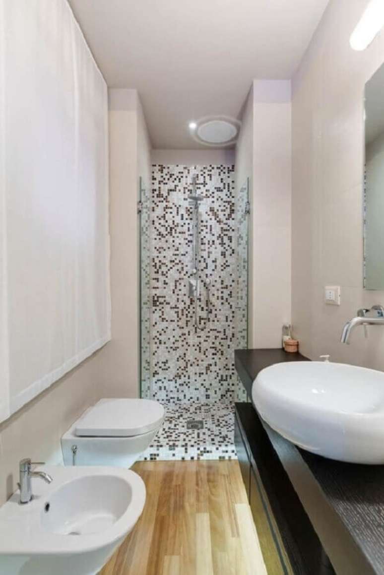 29. Decoração de banheiro com piso de madeira e pastilhas preta e branca – Foto: ArchZine