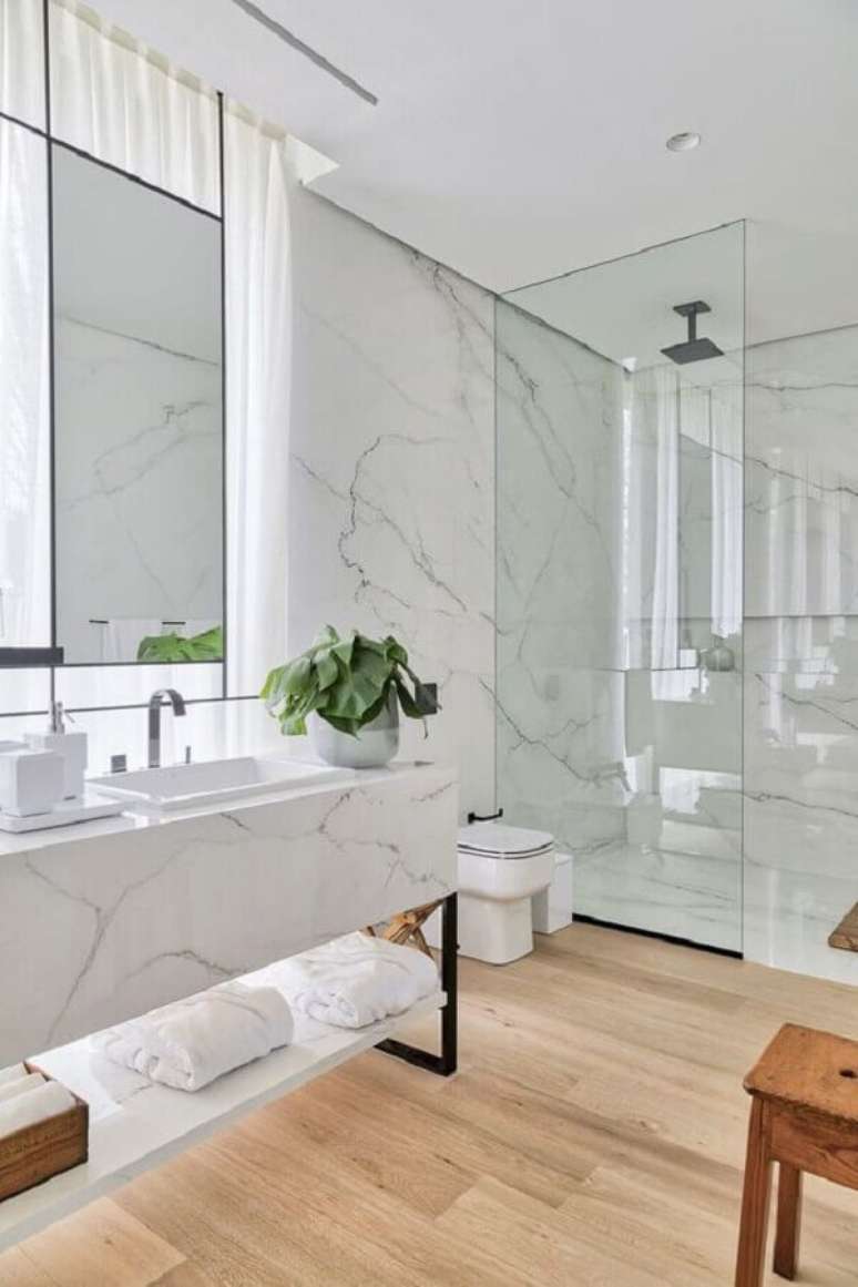 8. Decoração de luxo para banheiro com piso de madeira e bancada de mármore – Foto: HomeAdore