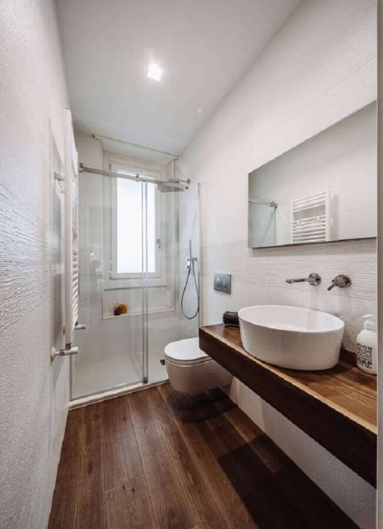 4. Decoração de banheiro pequeno com piso de madeira e espelho sem moldura – Foto: HomeAdore