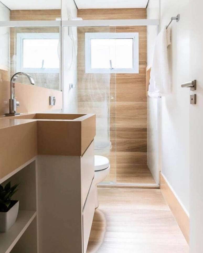 17. Banheiro pequeno com piso de madeira decorado com gabinete e bancada planejada – Foto: CW Arquitetura e Design