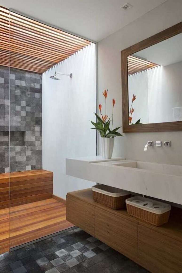 16. Banheiro com piso de madeira no box decorado com revestimento cinza quadriculado – Foto: Tripper Arquitetura